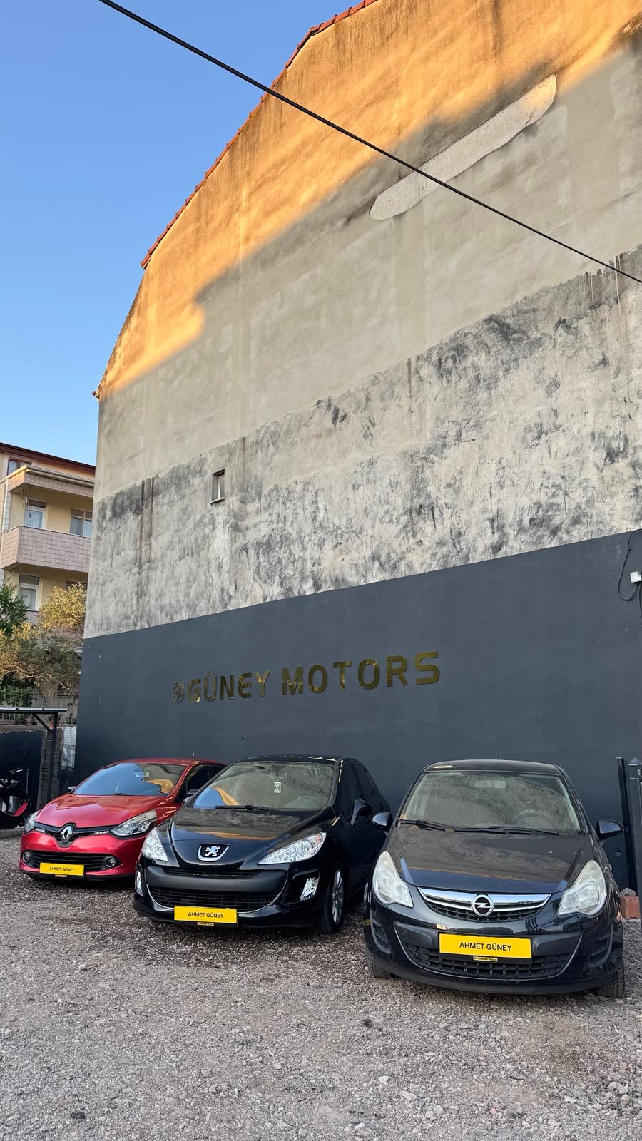Güney Motors duvarı önünde park halindeki araçlar