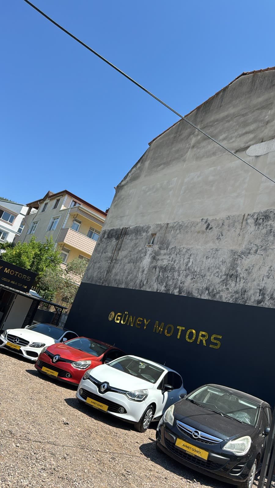 Siyah duvarda altın Güney Motors yazısı önünde sıralanmış araçlar